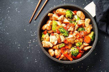 Sebzeli tavuk kızartması ve siyah arka planda susam. Geleneksel Asya mutfağı.