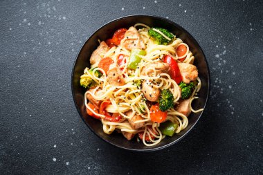 Kızarmış tavuğu sebzeyle karıştır ve siyah arka planda erişte. Asya mutfağı. Tasarım için alanı olan üst görünüm.