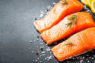 Somon fileto, biberiyeli taze balık ve siyah arka planda baharatlar..