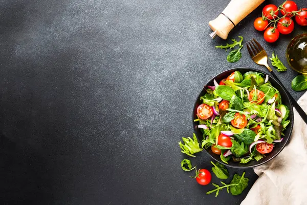Salata yapraklı yeşil salata ve siyah arka planda sebze. Kopyalama alanı olan üst görünüm.