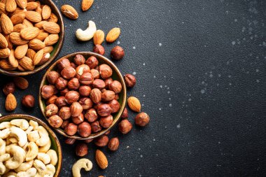 Siyah arka plandaki kaselerde fındık çeşitleri. Metin için boşluk ile düz uzandı.