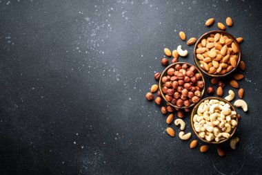 Siyah arka plandaki kaselerde fındık çeşitleri. Metin için boşluk ile düz uzandı.