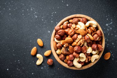 Siyah arka planda fındık çeşitleri. Badem, fındık, ahşap kasede kaju..