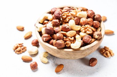 Beyaz arka planda fındık çeşitleri. Badem, fındık, ahşap kasede kaju..