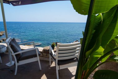 Yunanistan Girdisi, Akdeniz 'deki restoran. Denize yakın iki rahat sandalye. Geleneksel yaz tatili.
