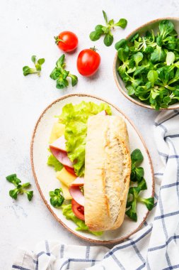Marul, peynir, domates ve jambonlu Ciabatta sandviçi. Düz beyaz masaya uzan..