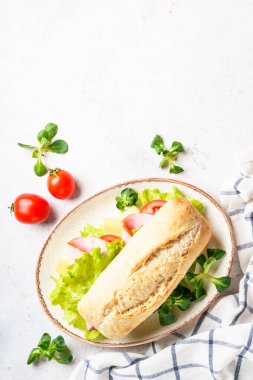 Marul, peynir, domates ve jambonlu Ciabatta sandviçi. Fast food, aperatif veya öğle yemeği. Kopyalama alanı olan beyaz üzerine üst görünüm.