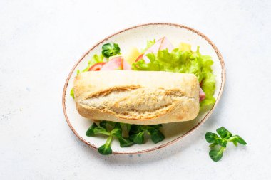 Marul, peynir, domates ve jambonlu Ciabatta sandviçi. Fast food, aperatif veya öğle yemeği. Beyaz üzerine üst görünüm.