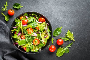 Arka planda siyah kasede salata. Sağlıklı yeşil sebze salatası, diyet menüsü. Üst görünüm.