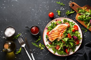 Sağlıklı yiyecekler. Siyah arka planda taze salatalı tavuk bifteği ızgara et. Kopyalama alanı olan üst görünüm.