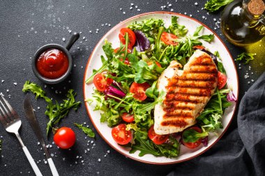 Sağlıklı yiyecekler. Siyah arka planda taze salatalı tavuk bifteği ızgara et. Üst görünüm.