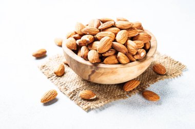 Beyaz arka planda tahta kasede badem fıstığı. Kapat..