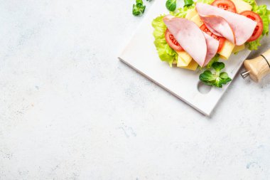 Marul, peynir, domates ve jambonlu sandviç. Sağlıklı fast food veya aperatif. Beyaz üzerine üst görünüm.