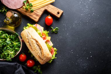 Marul, peynir, domates ve jambonlu sandviç. Mutfak masasında yemek için malzemeler var. Üst görünüm.