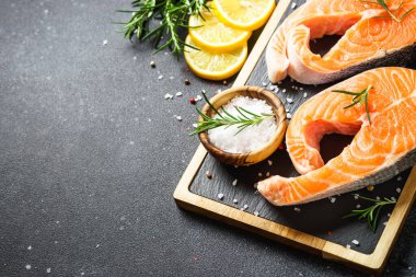 Siyah arka planda kesme tahtasında taze somon balığı bifteği.