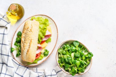 Marul, peynir, domates ve jambonlu Ciabatta sandviçi. Fast food, aperatif veya öğle yemeği. Kopyalama alanı olan beyaz üzerine üst görünüm.