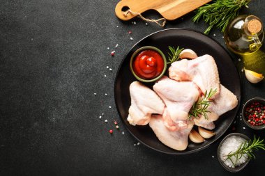 Tavuk kanadı, otlu çiğ tavuk eti. Siyah tablo üzerinde kopyalama alanı olan üst görünüm.