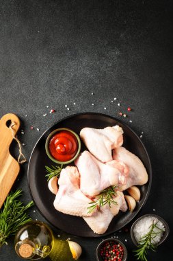 Tavuk kanadı, otlu çiğ tavuk eti. Siyah tablo üzerinde kopyalama alanı olan üst görünüm.