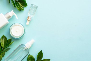Doğal kozmetik ürünleri mavinin üzerine saçılmıştı. Yeşil yapraklı krema ve serum..