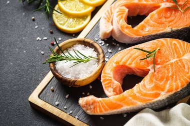 Siyah arka planda kesme tahtasında taze somon balığı bifteği. Makro.