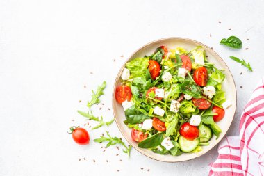 Ispanaklı yeşil salata, roka ve zeytinyağlı domates. Beyaz üzerine üst görünüm.