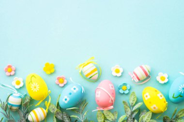 Paskalya arkaplanı ya da mavi kart. Yumurtalar, bahar yaprakları, çiçekler ve renkli kelebekler. Kopyalama alanı olan düz.