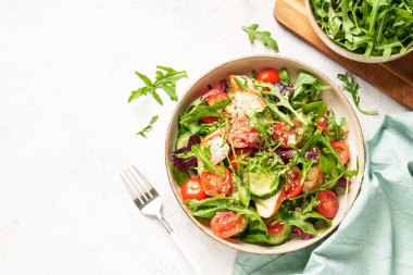 Fırında tavuk göğsü, taze salata yaprakları ve sebzeli yeşil salata. Beyaz arkaplanda üst görünüm.