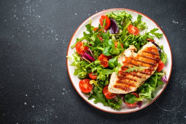 Sağlıklı yiyecekler. Siyah arka planda taze salatalı tavuk bifteği ızgara et. Üst görünüm.