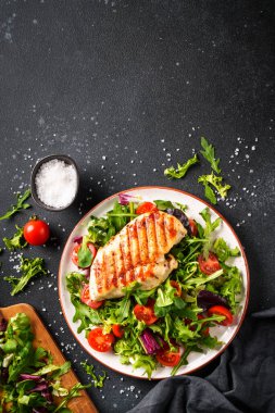 Sağlıklı yiyecekler. Siyah arka planda taze salatalı tavuk bifteği ızgara et. Üst görünüm, dikey görüntü.