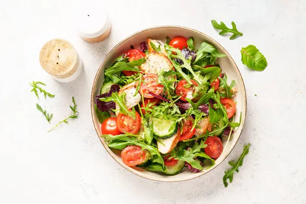 Sağlıklı yiyecekler. Fırında tavuk göğsü, taze salata yaprakları ve sebzeli yeşil salata. Beyaz arkaplanda üst görünüm.