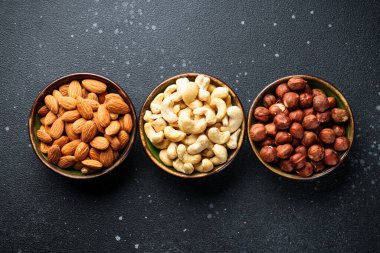 Siyah arka plandaki kaselerde fındık çeşitleri. Metin için boşluk ile düz uzandı.