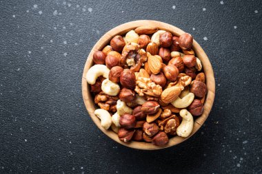 Siyah arka planda fındık çeşitleri. Badem, fındık, ahşap kasede kaju..