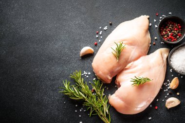 Siyah masada baharatlı pişmemiş tavuk göğsü. Kopyalama alanı olan düz.