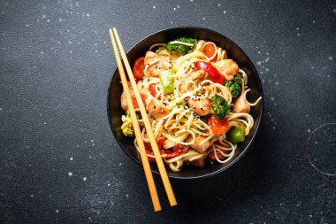 Kızarmış tavuğu sebzeyle karıştır ve siyah arka planda erişte. Asya mutfağı. Tasarım için alanı olan üst görünüm.