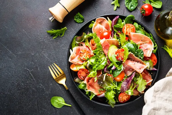 Groene Salade Zwarte Achtergrond Groene Saladebladeren Gerookt Vlees Tomaten Bovenaanzicht — Stockfoto