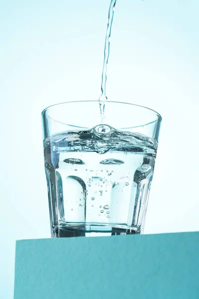 Gießen Von Wasser Glas Auf Blau Stockfoto