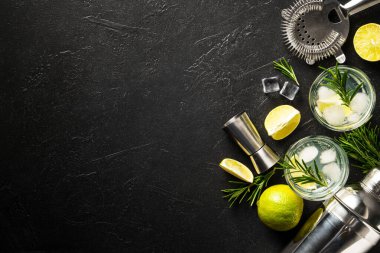 Cin toniği. Siyah arka planda cin, tonik, buz, limon ve biberiye karışımı. Kopyalama alanı olan üst görünüm.