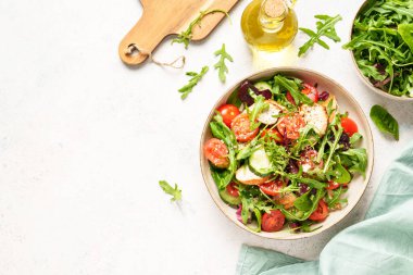 Beyaz masada sağlıklı yiyecekler. Fırında tavuk göğsü, taze salata yaprakları ve zeytinyağlı sebzeli yeşil salata. Kopyalama alanı olan üst görünüm..