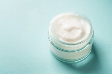 Mavi arka planda krema kavanozu. Cilt bakım ürünü. Kapat..