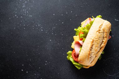 Marul, peynir, domates ve jambonlu sandviç. Mutfak masasında yemek için malzemeler var. Üst görünüm.