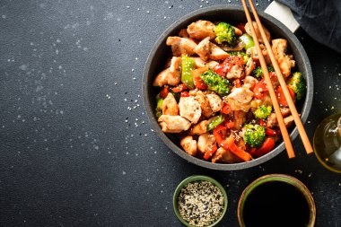 Sebzeli tavuk kızartması ve siyah arka planda susam. Geleneksel Asya mutfağı.