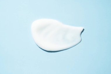 Kozmetik leke, mavi arka planda kremsi doku. Düz yatıyordu.