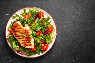 Dash diyeti. Tavuklu yeşil salata ve siyah arka planda taze sebzeler. Üst görünüm.