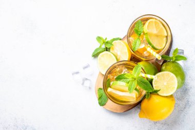 Limonlu buzlu çay, limon, nane ve buz. Soğuk limonata, yaz içkisi, beyaz arka plan. Kopyalama alanı olan üst görünüm.