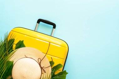 Yaz tatili, seyahat konsepti. Çanta, şapka ve palmiye yaprakları mavi arka planda. Metin için boşluk ile düz uzandı.