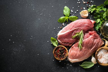 Baharatlı, otlu ve koyu arka planda yağlı çiğ et bifteği. Metin için boşluk olan üst görünüm.