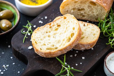 Tahtada ciabatta ekmeği, zeytin yağı, zeytin yağı ve siyah otlar. Akdeniz yemekleri.
