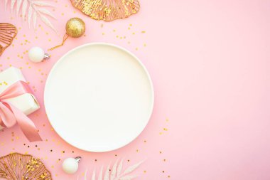 Pembe arka planda tabak, çatal bıçak ve Noel süslemeleri olan bir Noel masası. Kopyalama alanı olan düz resim.