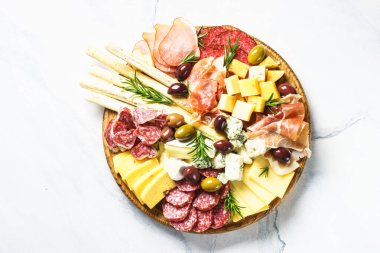Antipasto tabağı. Peynir ve et - jamon, salam, ahşap tahtada taş zeminde zeytin. Üst görünüm.