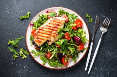 Dash diyeti, sağlıklı beslenme. Siyah arka planda taze salatalı tavuk bifteği. Kopyalama alanı olan üst görünüm.